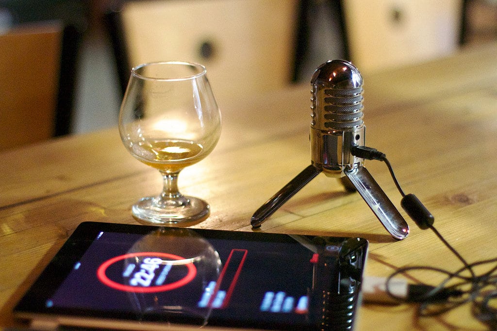 Podcast setup with a small wine glass, microphone and iPad